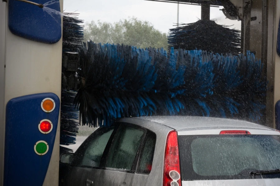 Voiture recouverte de mousse active pendant le lavage de la voiture entrant dans les brosses d'une machine à laver sur fond flou