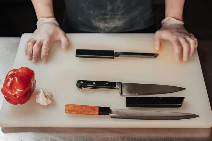 Colpo del primo piano dei coltelli da cucina sul tagliere bianco