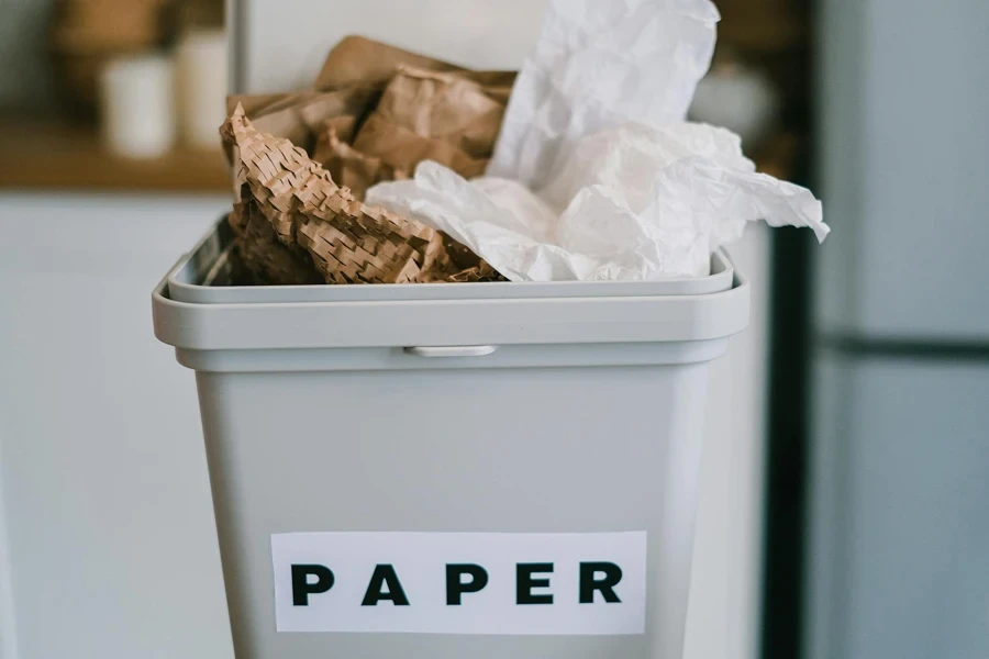 Closeup de recipiente de plástico cheio de papel colocado em fundo desfocado da cozinha durante o dia