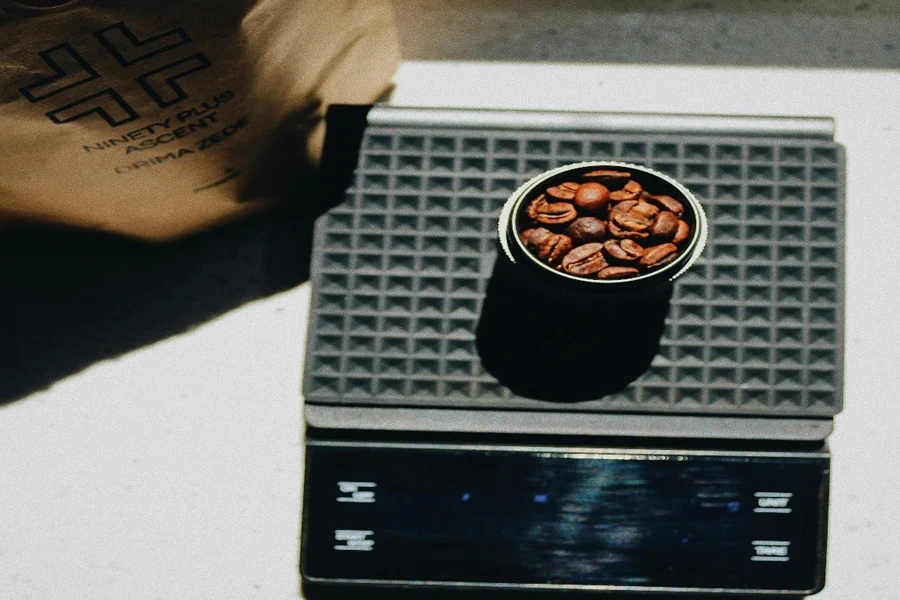 Contenitore con chicchi di caffè in piedi su una bilancia da cucina