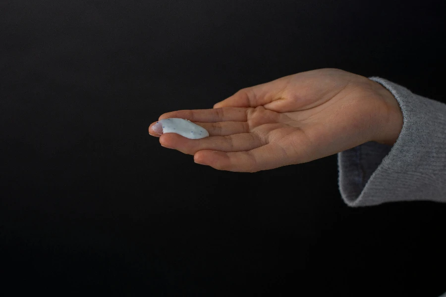 Crop unrecognizable person showing cream on hand