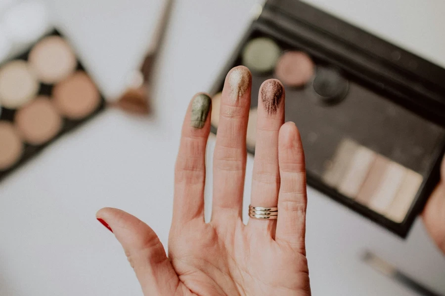 Diferentes colores de sombras de ojos probándose en las yemas de los dedos de una mujer.