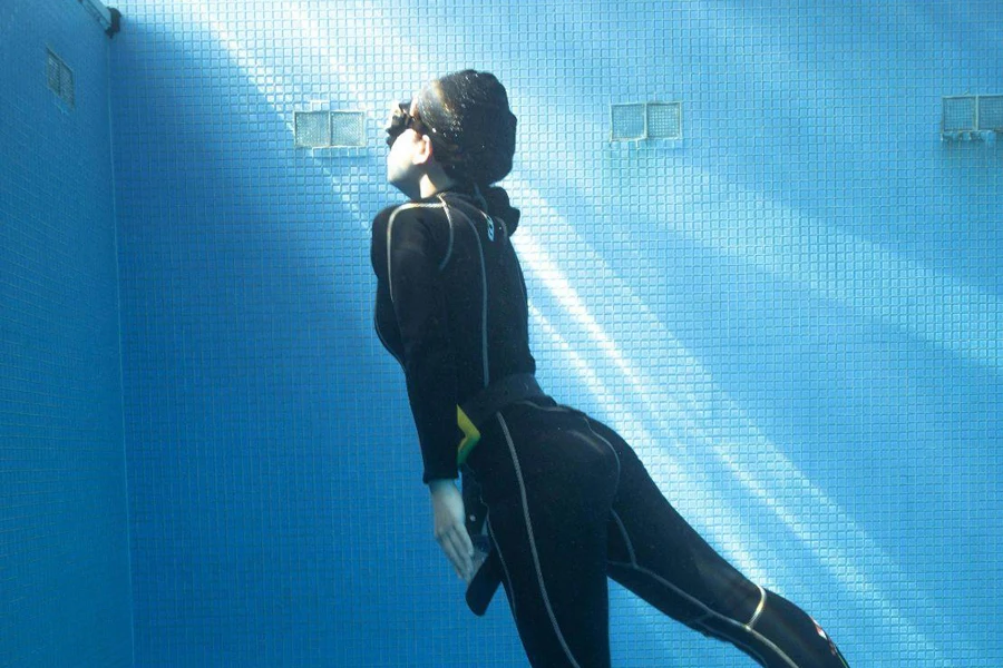 Faceless woman diving underwater in pool