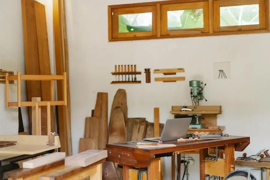 Laptop placed on table in woodworker workshop by Ono Kosuki