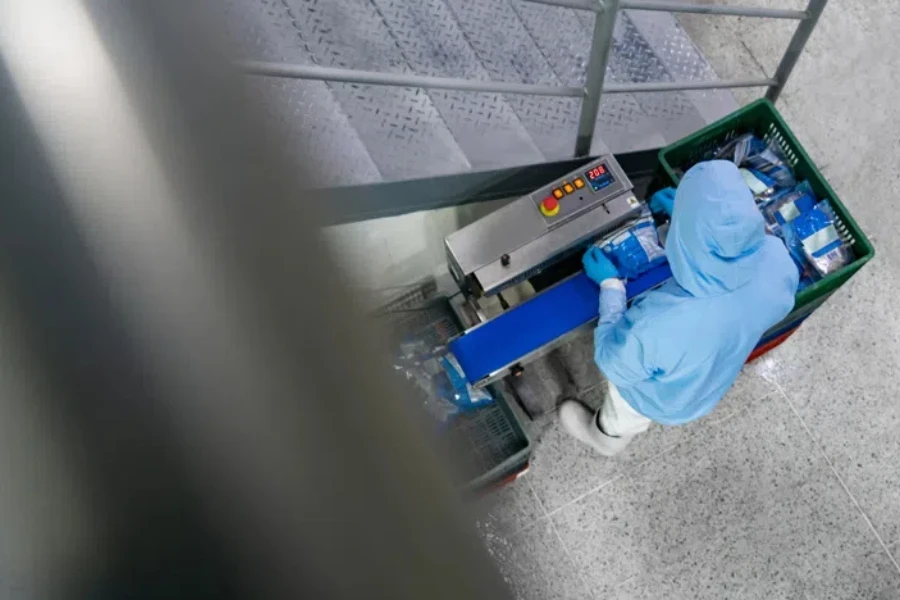 Latin American worker packing seafood at a food processing plant using a vacuum sealer