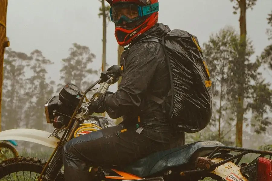 Male motorcyclist in helmet riding in forest by Labskiii