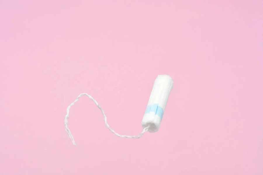 Tampon flyeng medis wanita dengan latar belakang merah muda