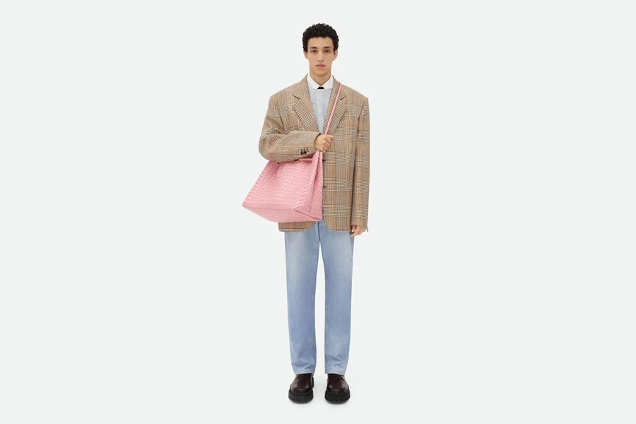 Modelo vestindo uma grande bolsa Andiamo nas costas na cor rosa chiclete, retratando luxo alto