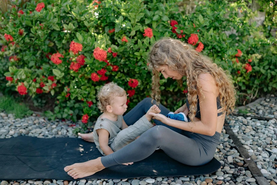 Madre e figlio che riposano sulla stuoia di yoga in giardino