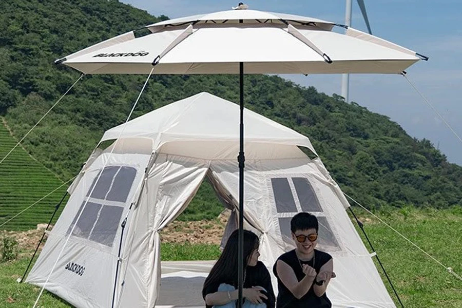 People sitting outside a tent with a beach umbrella