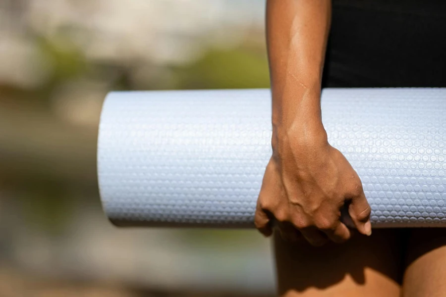 Person Holding White Rolled Exercise Mat