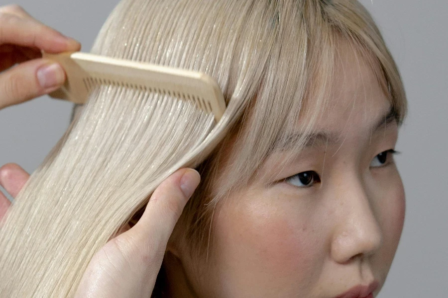 Photographie des mains d'une personne peignant les cheveux d'une femme