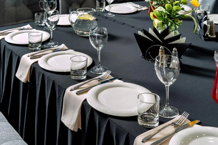 Tischdekoration für eine Hochzeit oder ein Abendessen, schwarze Tischdecke, weiße Teller