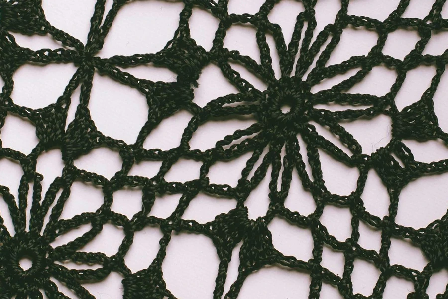 Textured background of knitted floral ornament with holes