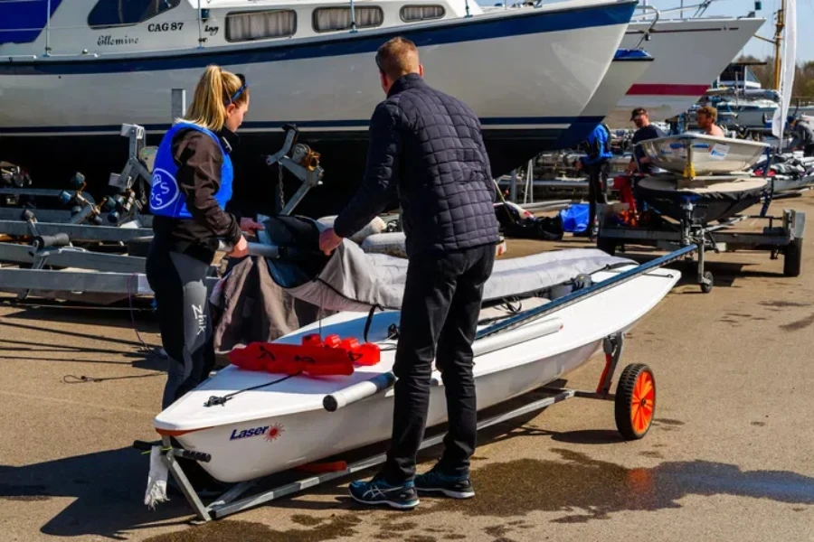 Zwei Personen verstauen einen Laser-Segelbootmast nach Gebrauch in einem Koffer