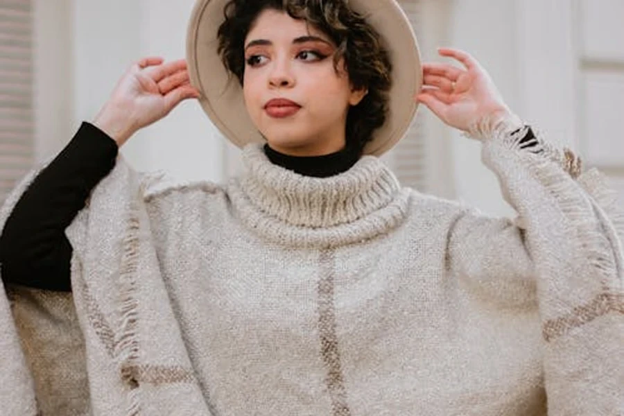 Woman in a short cream poncho with big collar and fringe