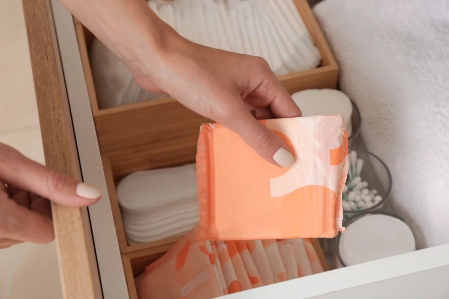 Woman taking disposable menstrual pad from drawer at home