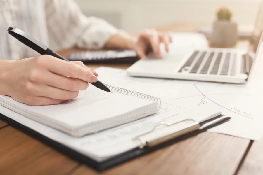 Manos de mujer escribiendo en un bloc de notas