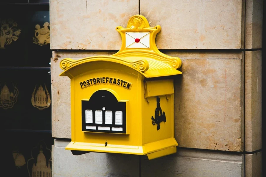 Boîte aux lettres flottante Postbriefkasten jaune sur mur en béton marron