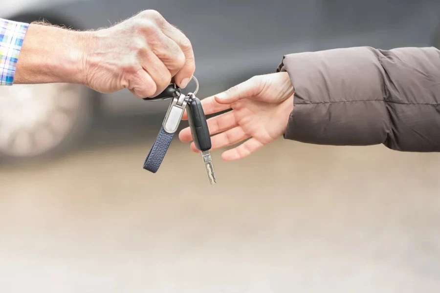 chave-do-carro-entrega-empresário-uma-jovem-mulher-na-frente-do-carro-borrado