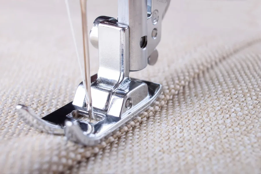 odern sewing machine presser foot with linen fabric and thread, closeup