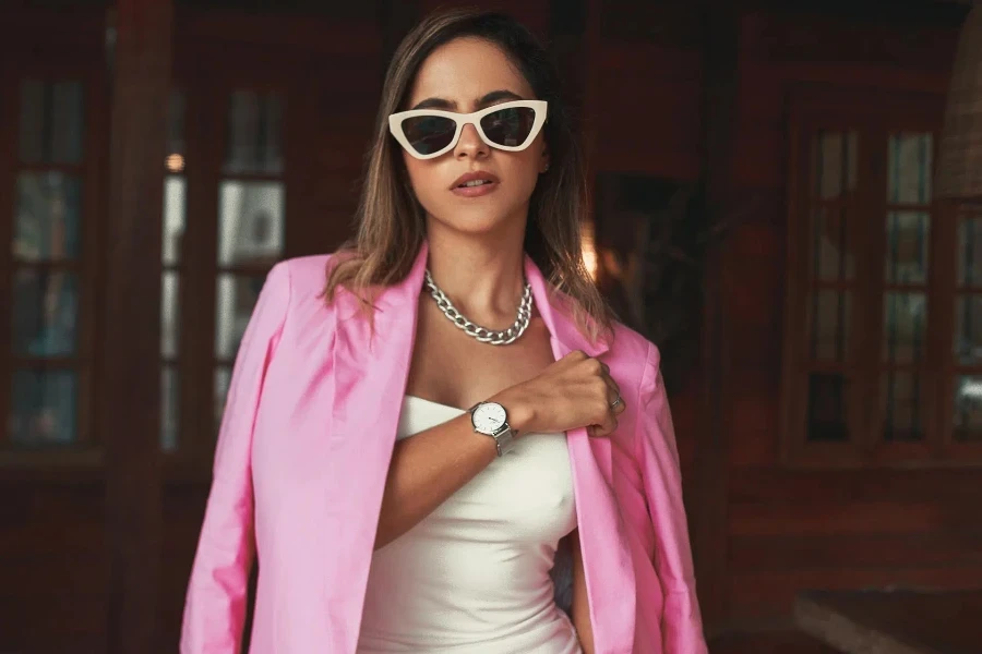 Wanita berdiri dengan blazer merah muda dan gaun putih