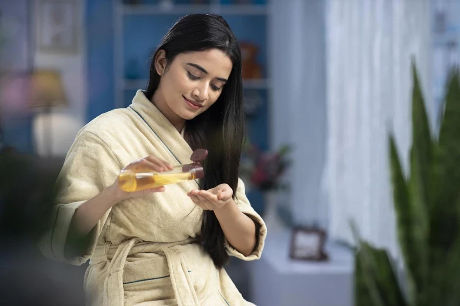 wanita muda, bahagia, melamar, minyak, perawatan rambut, India, etnis India