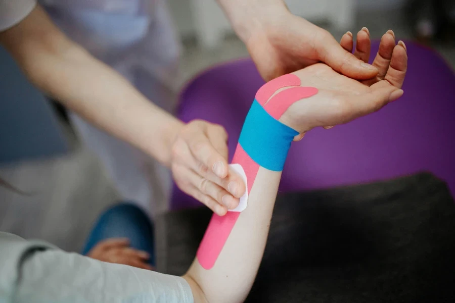 A Person Putting Kinesio Tape on Client's Arm