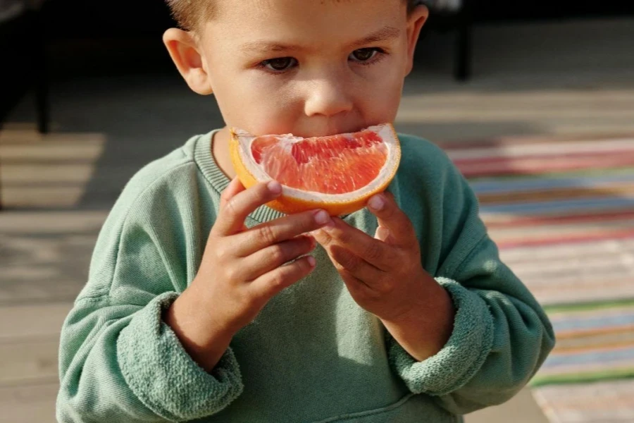 Un jeune garçon mangeant du pamplemousse