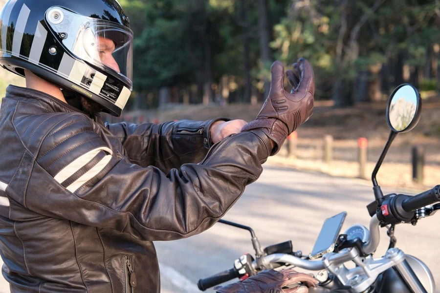 Um motociclista calça luvas antes de andar de moto