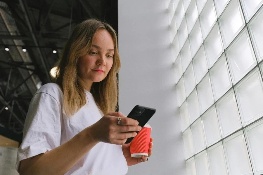 Uma pessoa segurando um telefone e uma xícara