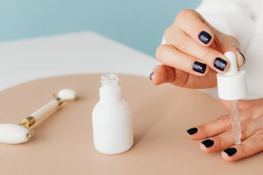 Una mujer aplicando aceite en las cutículas de sus uñas.