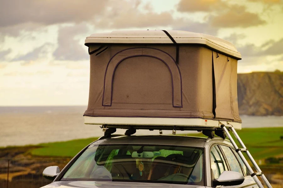 Voiture avec camp de tentes sur le toit au bord de la mer