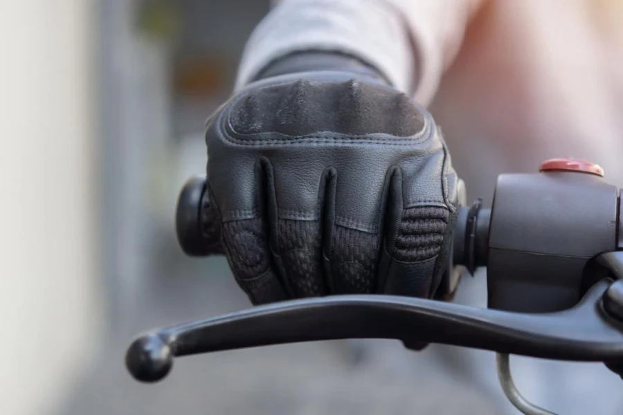 La mano di un uomo con guanti protettivi da moto tiene una moto nera