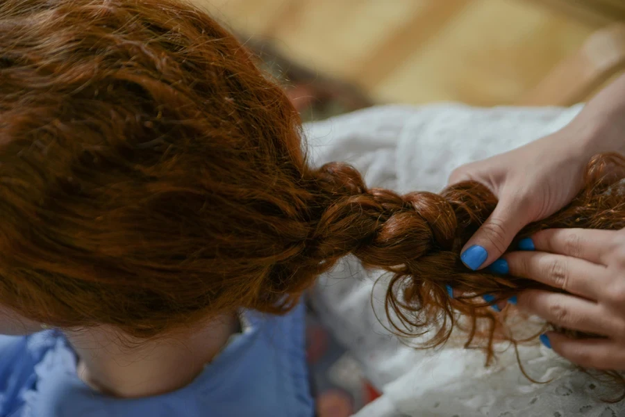 Mani che intrecciano i capelli di una donna