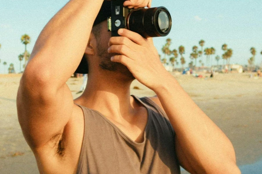 Homem usando câmera DSLR enquanto está na praia