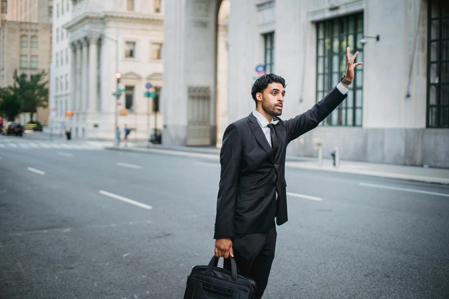 Man in Black Suit Jacket Standing and Waving Hand on Road