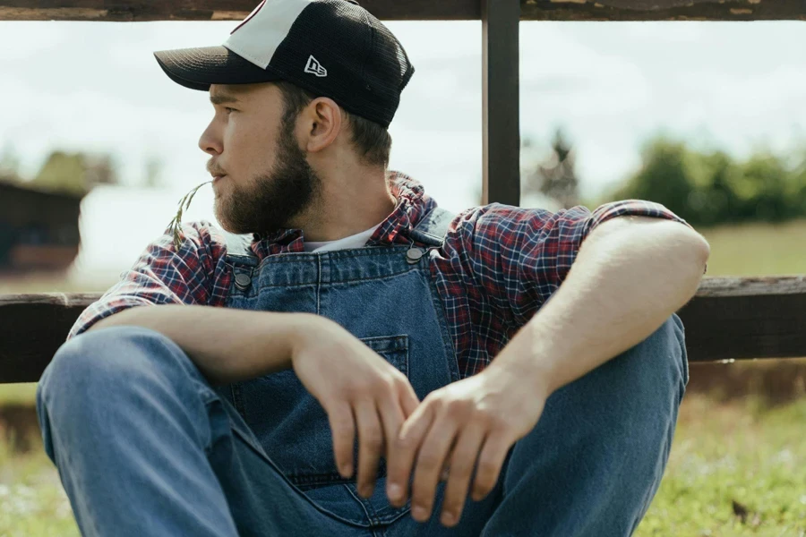 Homem de colete jeans azul e boné preto sentado