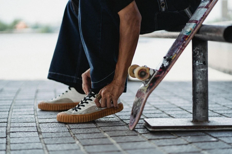 Uomo in denim che tocca le scarpe da ginnastica