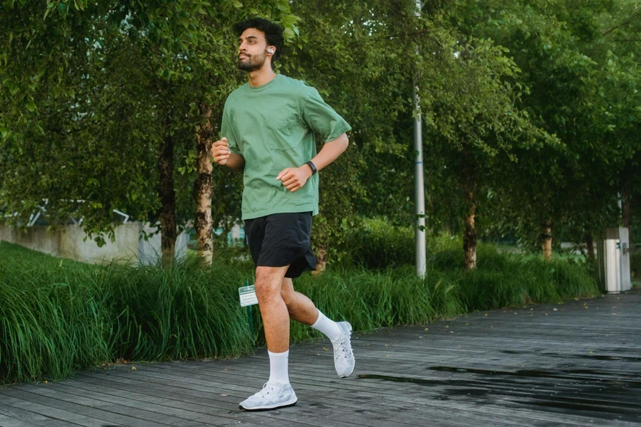 Man in Green T-shirt and Black Shorts Running on the Park