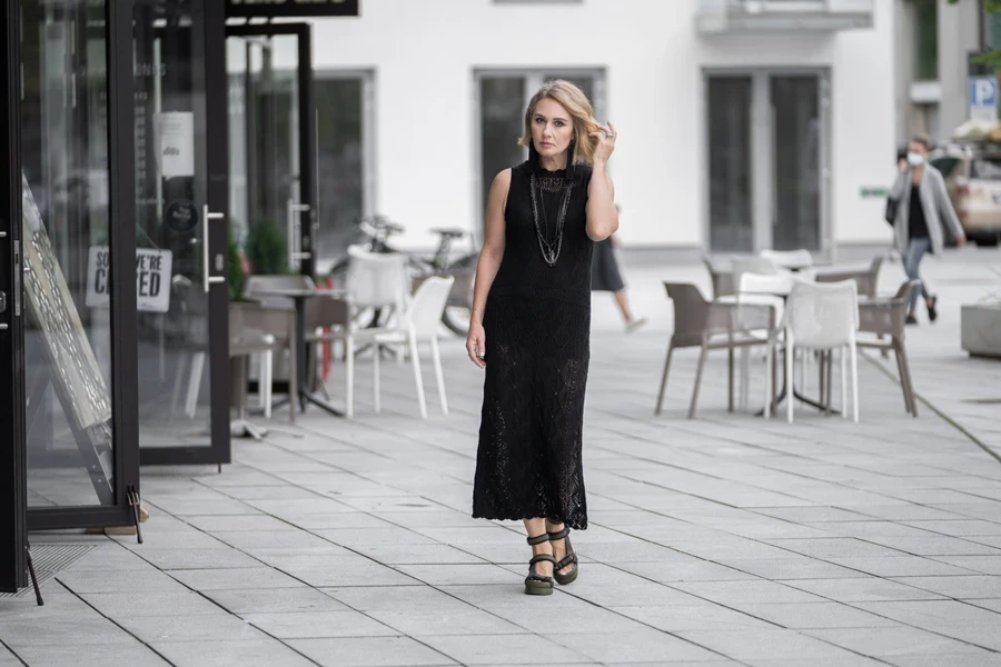 Mujer madura con un vestido negro largo y clásico y sandalias.