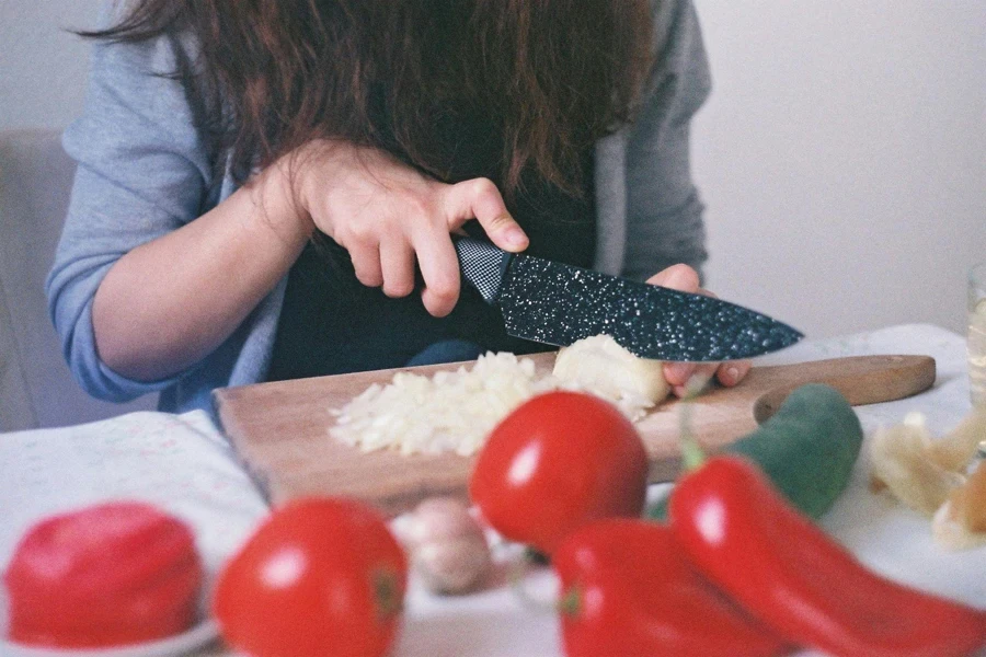 Person Cutting Vegetables on Chopping Board