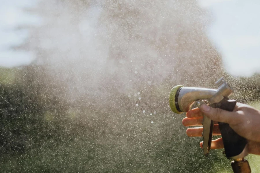 Mano della persona che usa un tubo flessibile spray