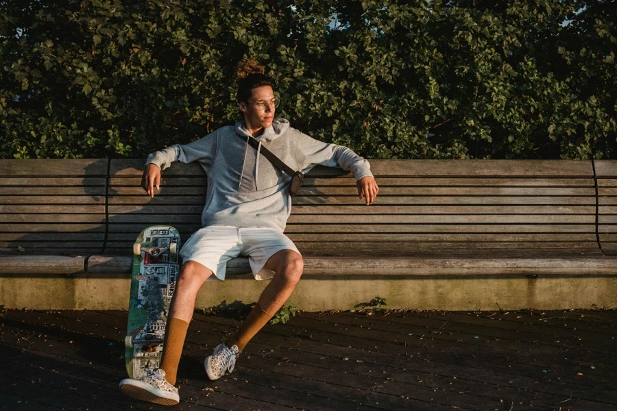 Thoughtful Skateboarder on Bench in Park