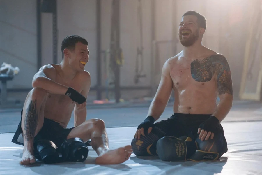 Two male boxers sitting on the floor wearing mouthguards