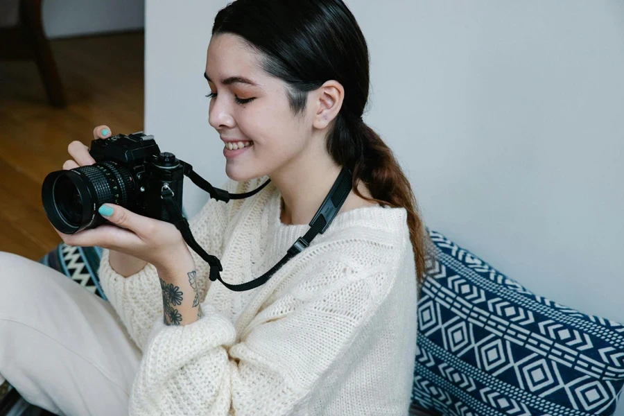 Femme En Tricot Blanc Tenant Un Appareil Photo Noir