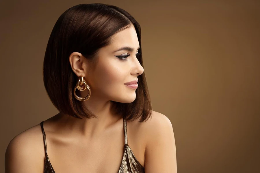 Portrait de profil de femme avec boucle d'oreille dorée, coiffure bob sur brun foncé