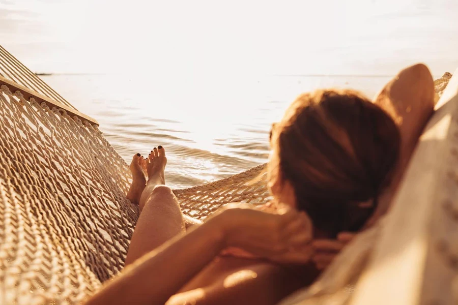 Young woman relaxing in wicker hammock on the sandy beach