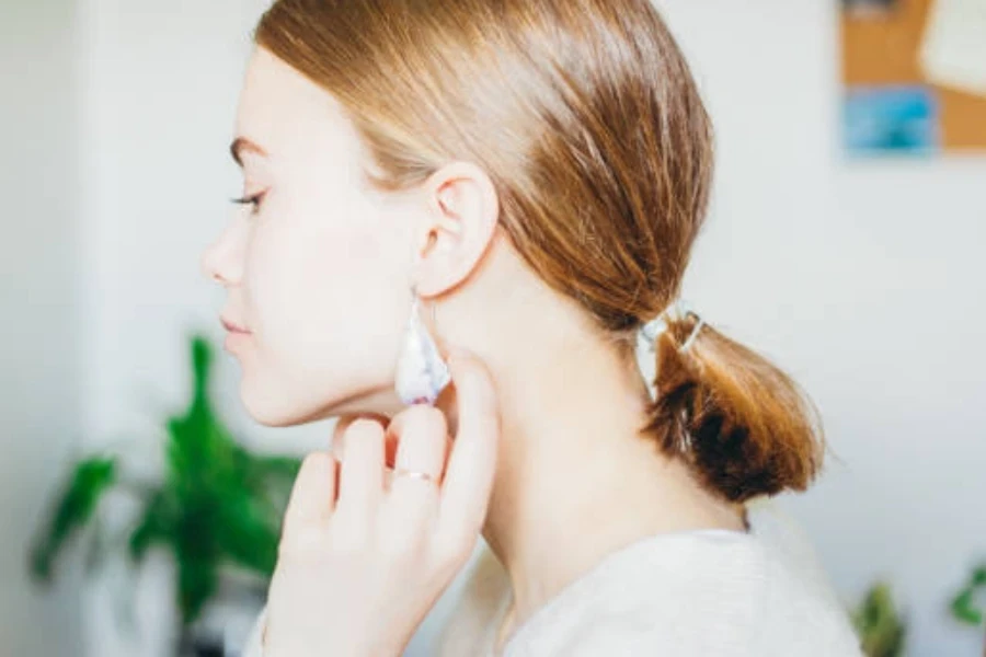 Une jeune femme essaie ses nouvelles boucles d'oreilles en coquillage