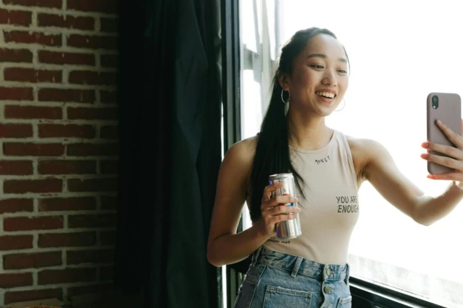 a female in a tank top making a video with a product in her hand